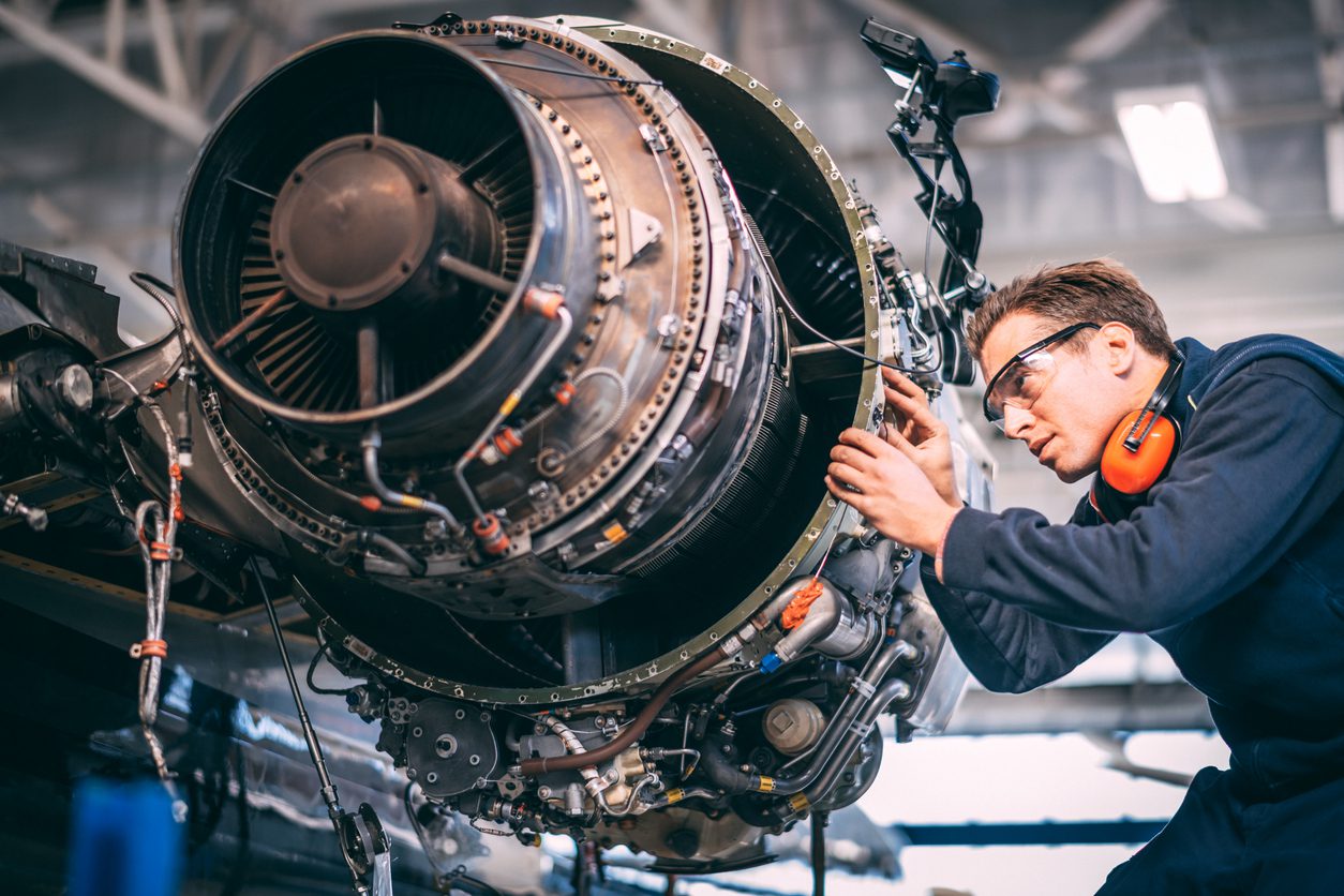 Aircraft mechanic in a hangar repairing and maintaining a small airplane’s jet engine